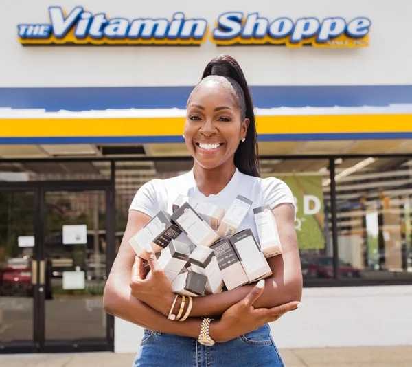 Black female smiling as she holds a large quantity of packaged goods in her arms
