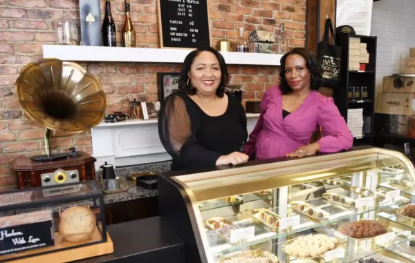 Two African American women stand at the counter of a sweet store smiling