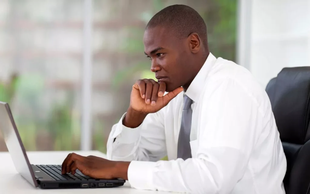 An african american black man in a suit is looking for a job on a computer