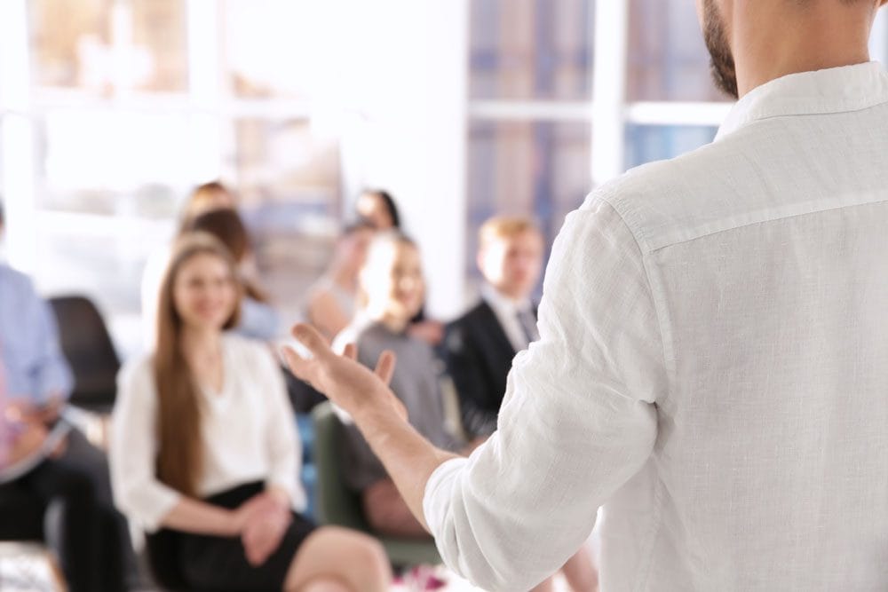 Back view of a man giving a speech to an audience