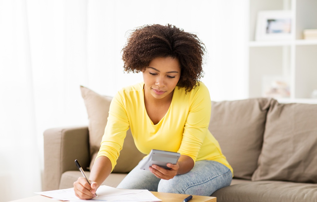 african woman with papers and calculator at home