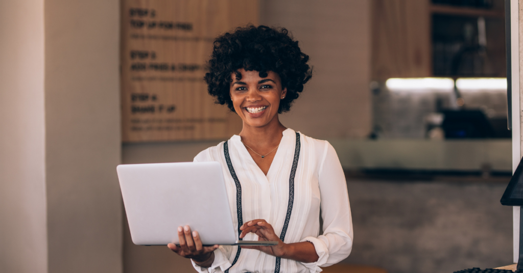 woman business owner smiling holding laptop