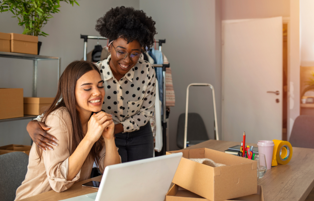Two diverse women small business owners excited at what's on computer screen