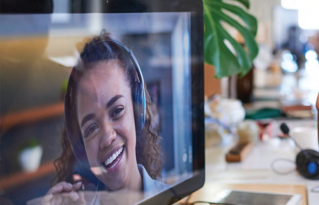 Woman shown on computer screen wearing a headset and smiling